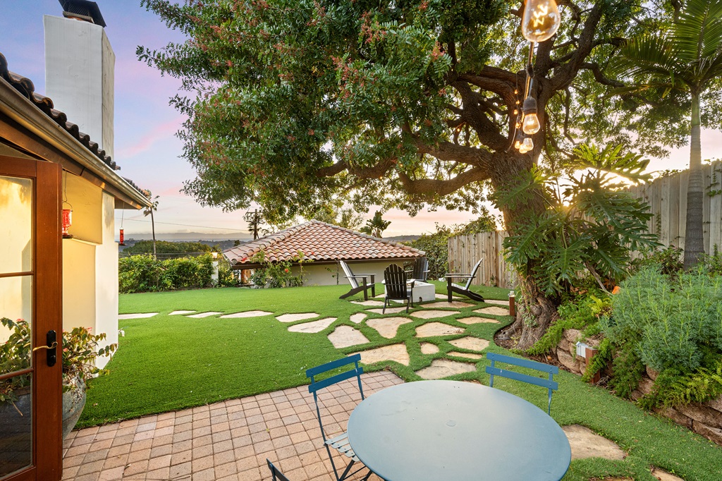 a small backyard with a blue table, chairs and a large tree