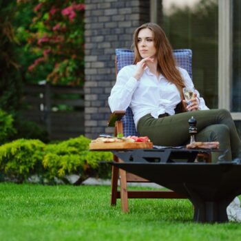 Beautiful woman sits on folding chair on backyard and looking to the side