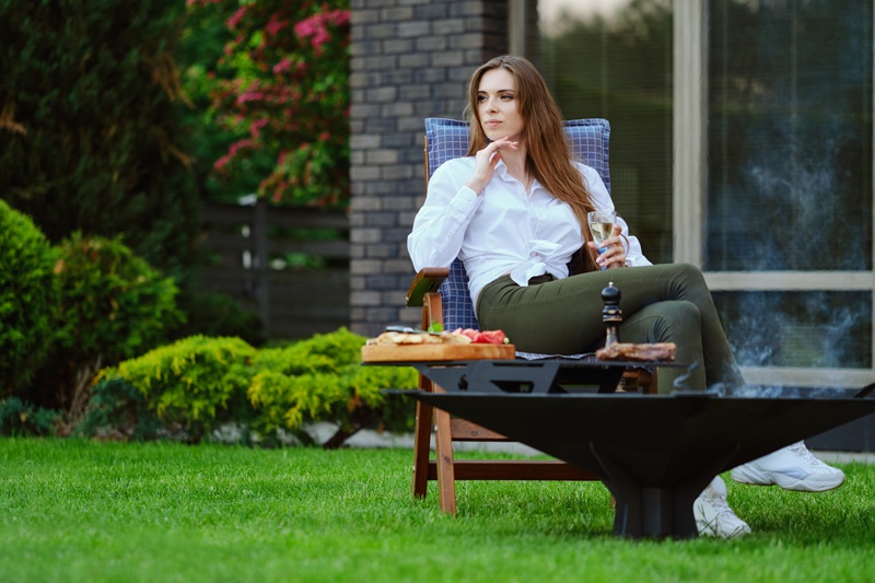 Beautiful woman sits on folding chair on backyard and looking to the side